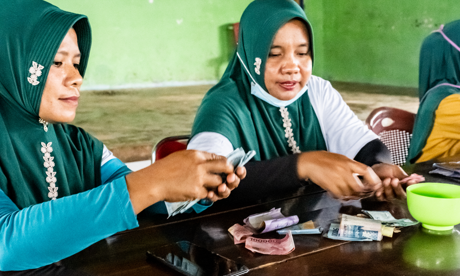 Wa Sani (left) and Darniawati counting savings deposits being made at a savings club meeting in Pasi Kolaga.