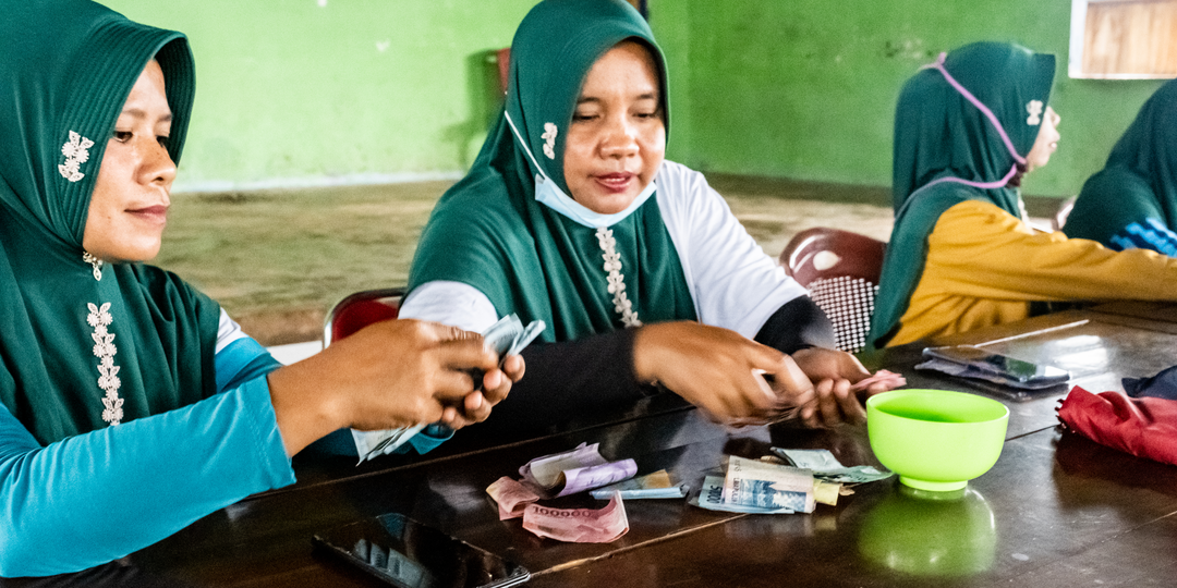 Wa Sani (left) and Darniawati counting savings deposits being made at a savings club meeting in Pasi Kolaga.