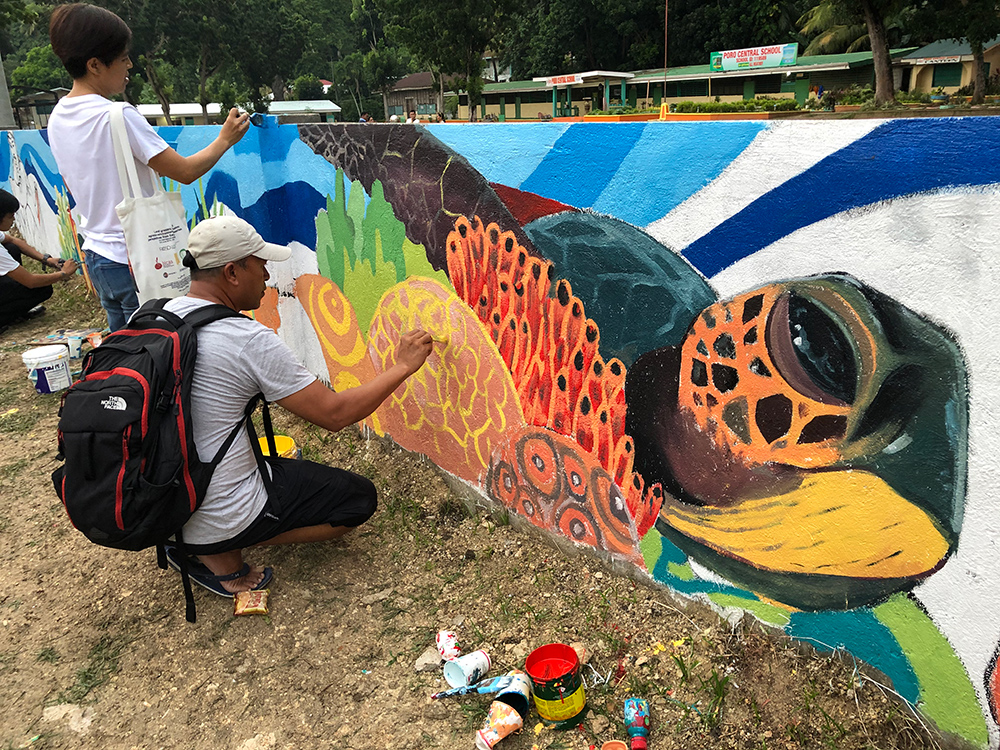 Poro man painting mural.