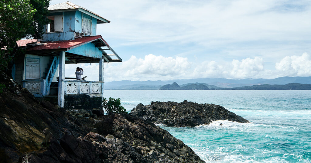 Man with binoculars looking out into the ocean in the Philippines.