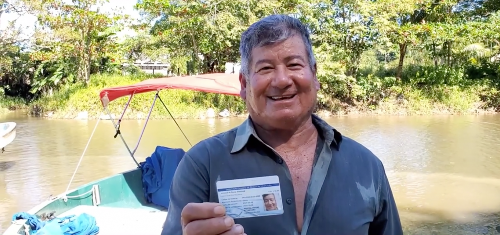 Photo of a smiling fisherman holding his new registration card.