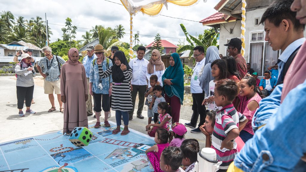 Rare Board of Trustees watching local community members play Snakes and Ladders, a game that teaches them the elements of Fish Forever in Mola, Wakatobi, Southeast Sulawesi.