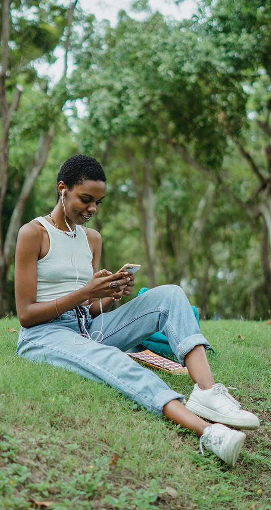 Black woman listening to music in a park.