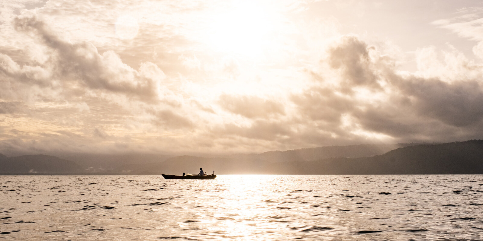 Fisher during sunrise off the coast.