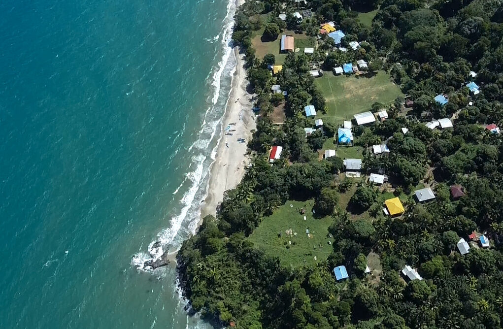 Aerial photo of the ocean along the coast of a small town in Plan Grande, Honduras.