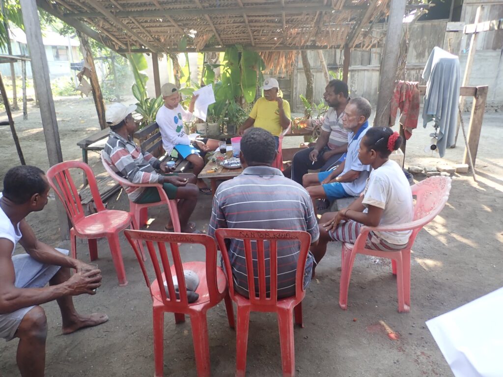 A group of people sitting around a table in Indonesia learning catch recording and reporting.