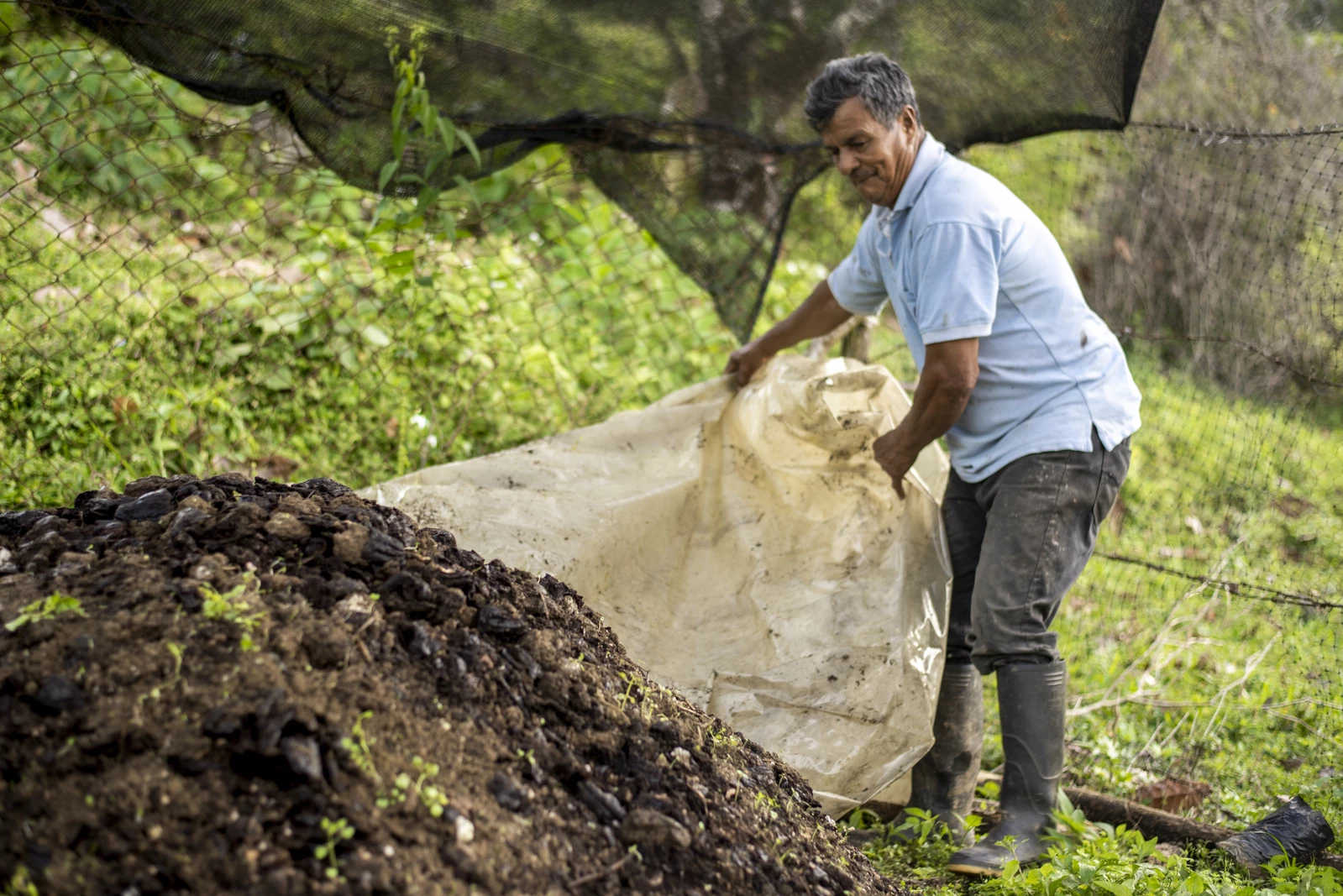 A male farmer making a pile of compost.