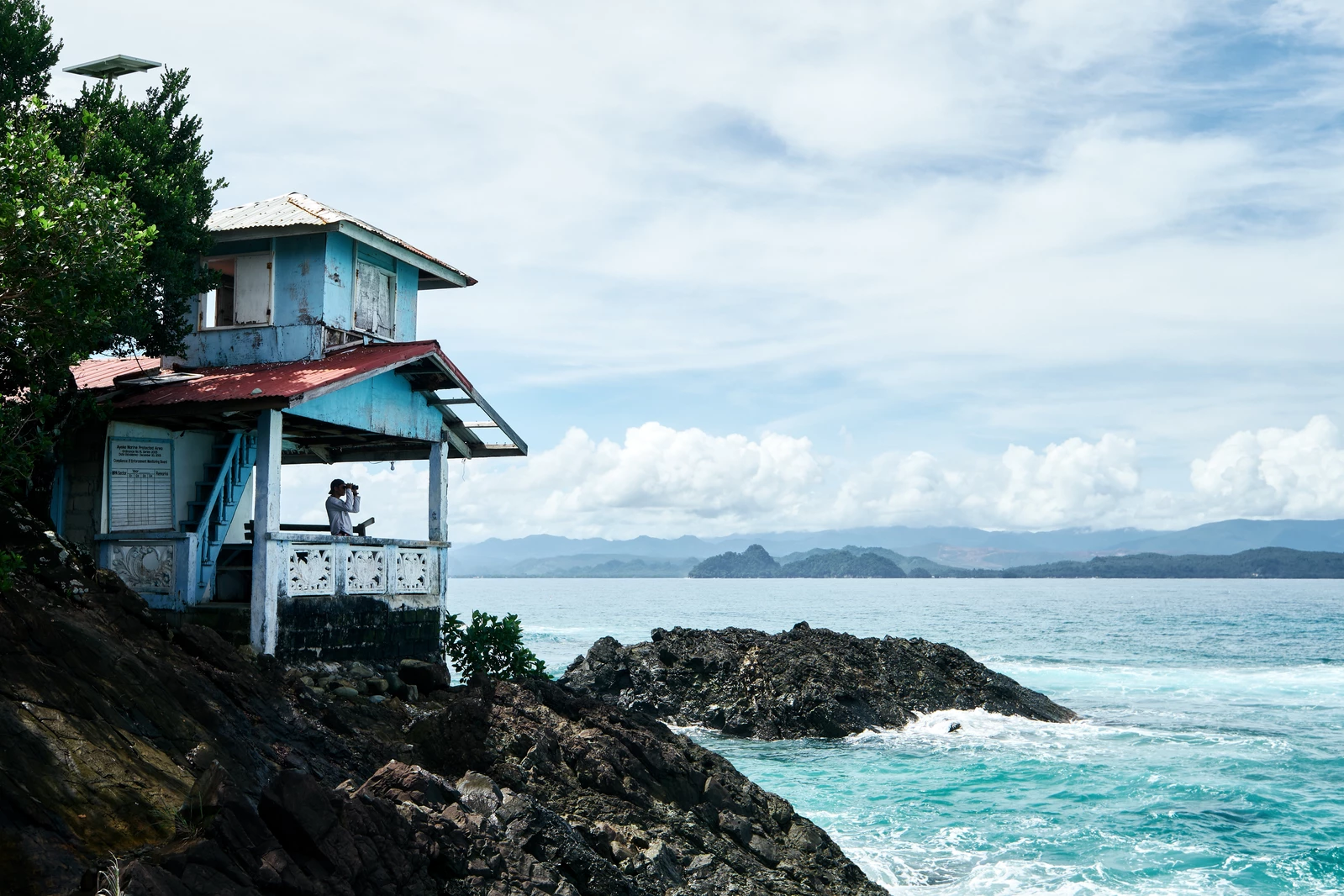 Man in fishing guardhouse along rocky shores of the ocean in the Philippines.