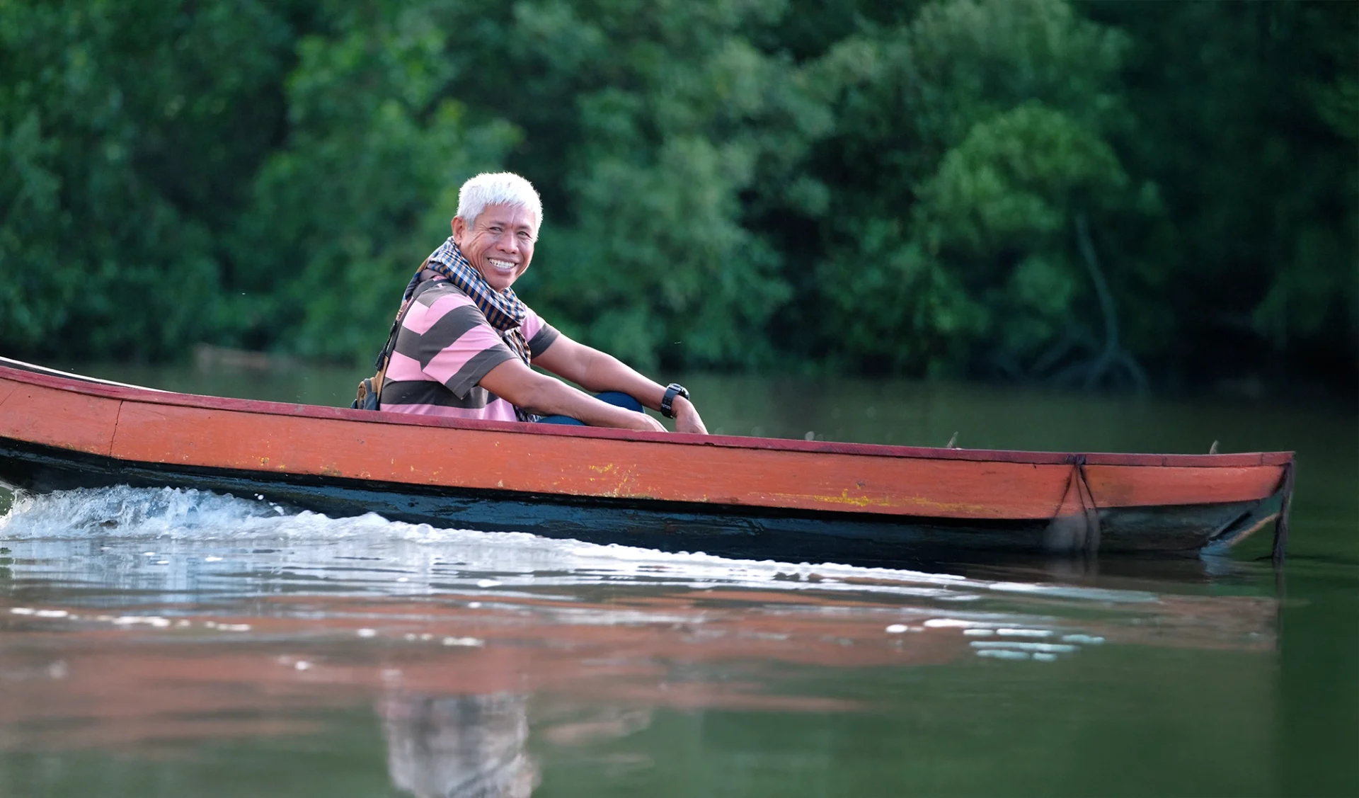 Roberto Ballon Jr., affectionately named “Ka Dodoy” by fellow fisherfolk, is smiling at the camera from his red canoe in Zamboanga Sibugay, Philippines.