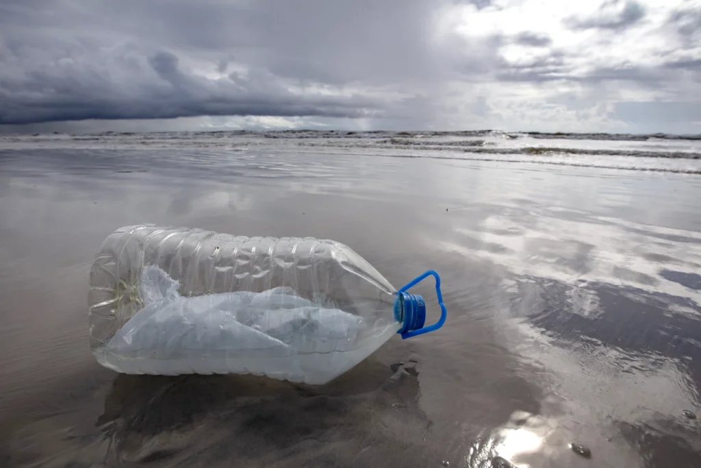 plastic jug with a plastic bag inside it on a beach