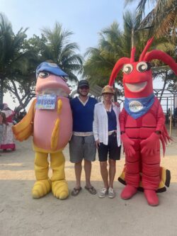 Photo of Slater McLean and Amy Margerum Berg (Board Member) with local mascots at a community event in Santa Fé with Rare's Board of Trustees to celebrate the approval and declaration of Honduras’s second community-managed fishing area.