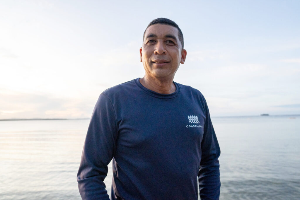 a portrait of a man in blue long-sleeve shirt, ocean background