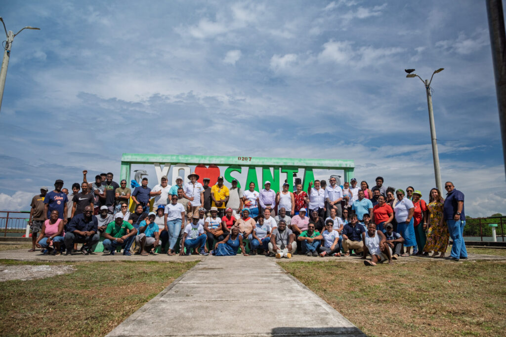 a group photo of fishers and community leaders in front of wooden Santa Santa Rosa de Aguán sign