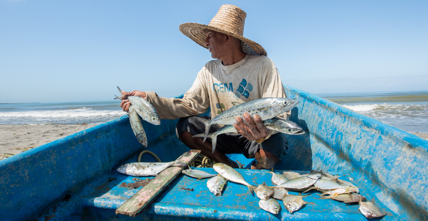 Omar Garcia, a local fisher in Omoa, holding his catch in a blue boat.
