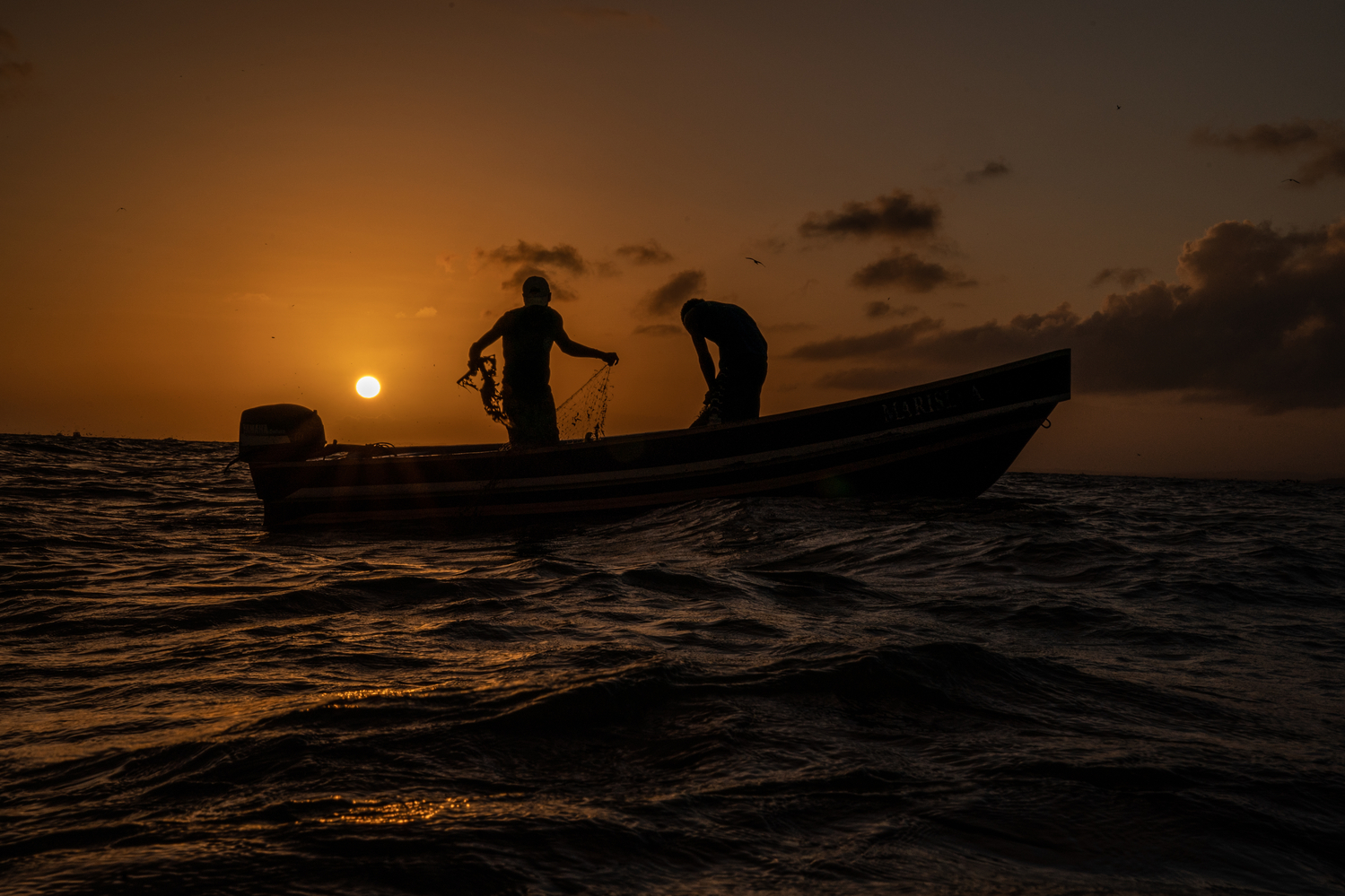 Two fishermen on their boat at sunset in Guatemala.