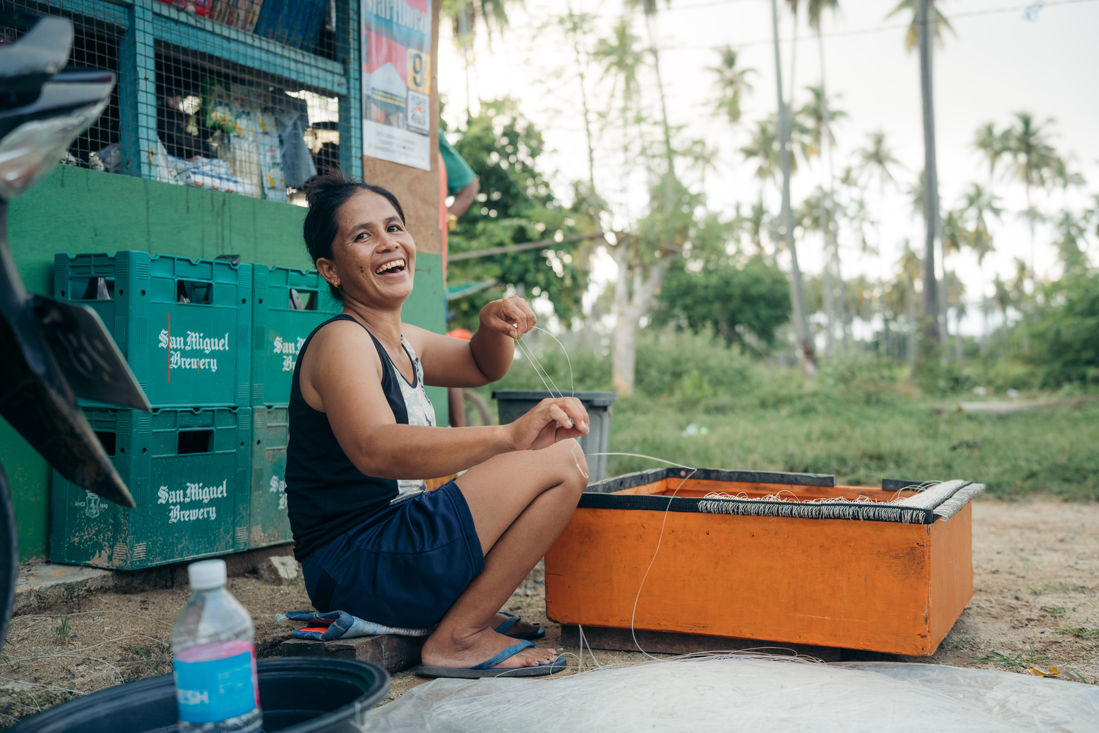 a woman smiles while sitting and working on a net