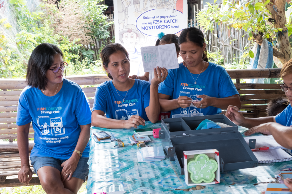 three women sitting on a bench at a table partaking in a meeting