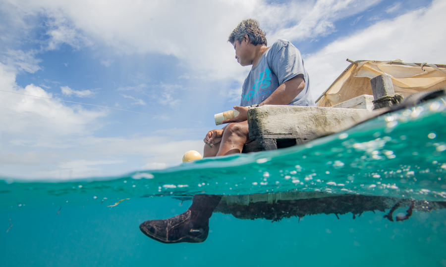 Ur, a Melekeok local with significant vision problems, relies on fish catch to supplement her family's food. She's pictured here line fishing from a raft towed from the shore by local friend, Omar Fasutino.